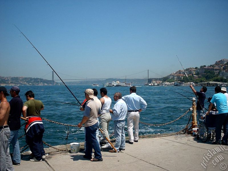 View of fishing people and on the horizon Bosphorus Bridge from Uskudar shore of Istanbul city of Turkey.

