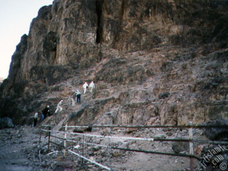 The cave located in the skirt of the Mount Uhud and the pilgrims climbing it.
