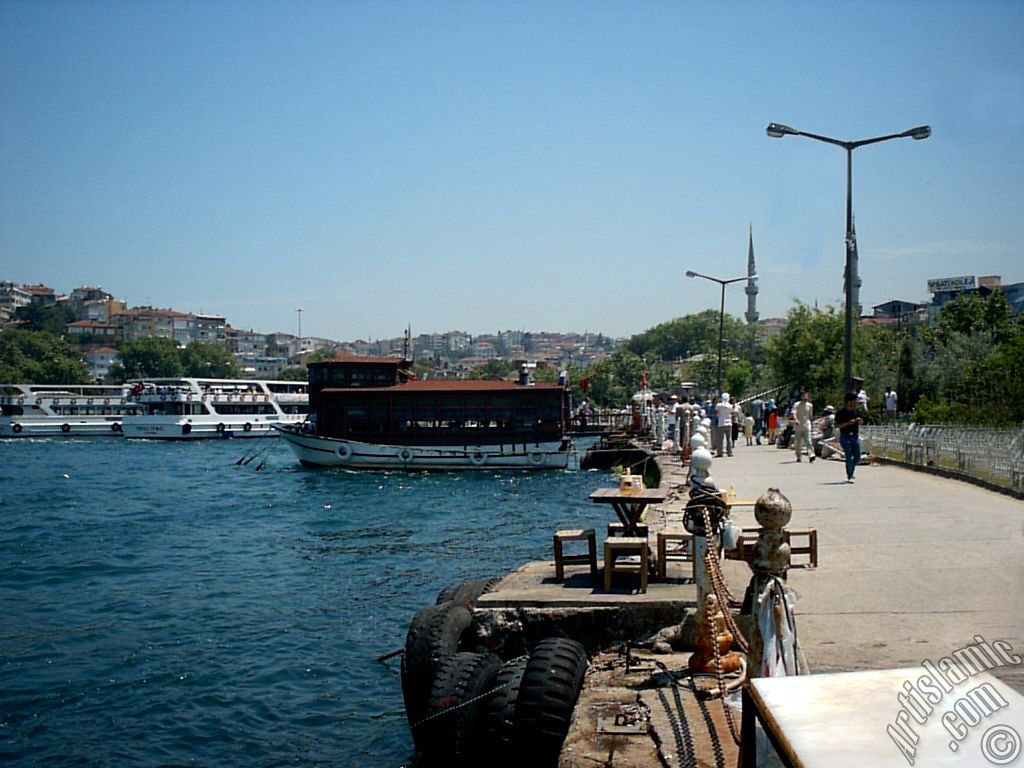View of the shore, a fisher boat and Mihrimah Sultan Mosque`s minarets in Uskudar district of Istanbul city of Turkey.
