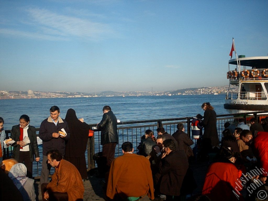 View of people eating sandwich with fish from the shore of Eminonu in Istanbul city of Turkey.
