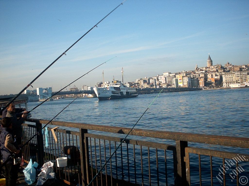View of fishing people, a landing ship, Galata Bridge and Galata Tower from the shore of Eminonu in Istanbul city of Turkey.
