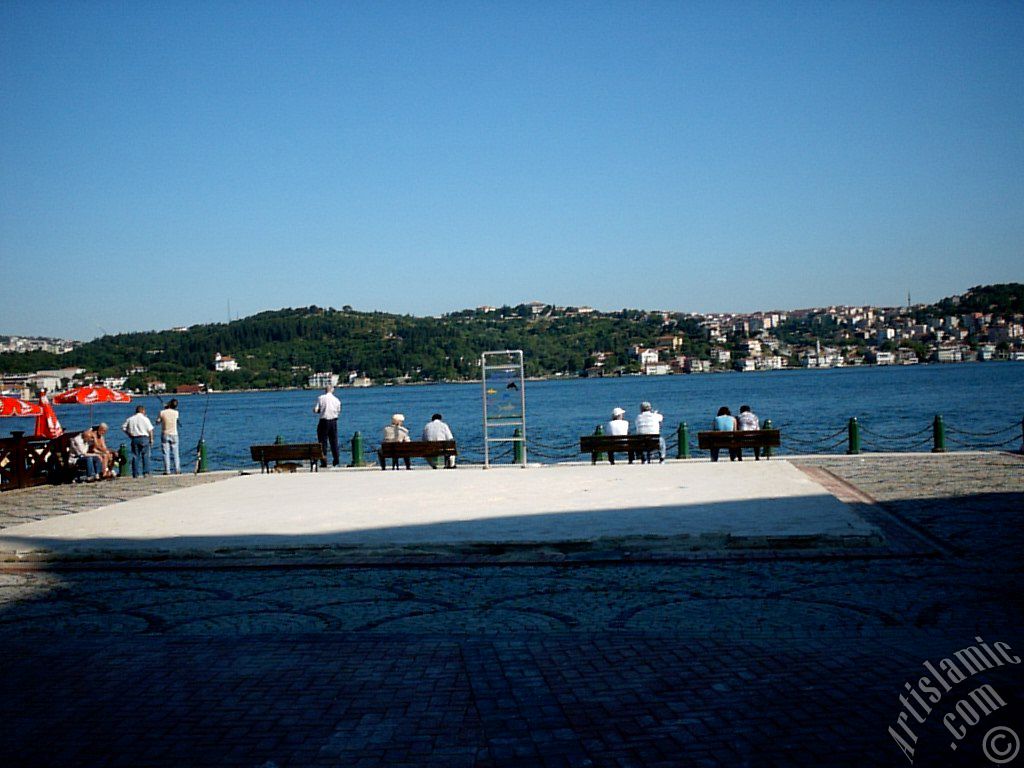 View of fishing people and Uskudar-Beylerbeyi coast on the horizon from a park at Ortakoy shore in Istanbul city of Turkey.
